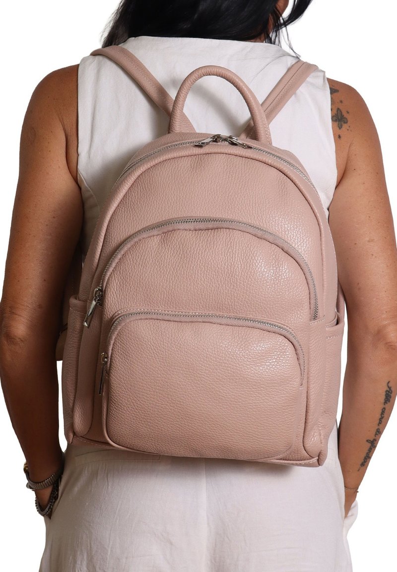 Zaino in pelle rosa con più scomparti con zip, forma arrotondata, superficie testurizzata e manico superiore. Le cinghie sono regolabili.