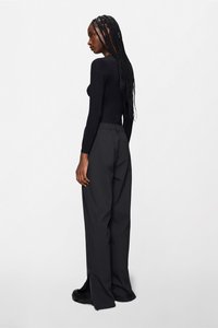 Μαύρο μακρυμάνικο τοπ και φαρδιά μαύρα παντελόνια, κατασκευασμένα από λείο ύφασμα, με ελαστική μέση και σχέδιο με ίσια πόδια.