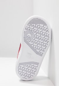 Vit sneakersula med detaljerade strukturerade mönster, med cirkulära och linjära designinslag; präglad med "adidas"-logotypen för varumärkesidentifikation.