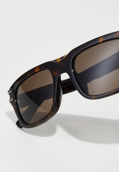 Ochelari de soare brown cu modele de schildpadă, cu rame mari, pătrate, având lentile întunecate și un finisaj neted, lucios.