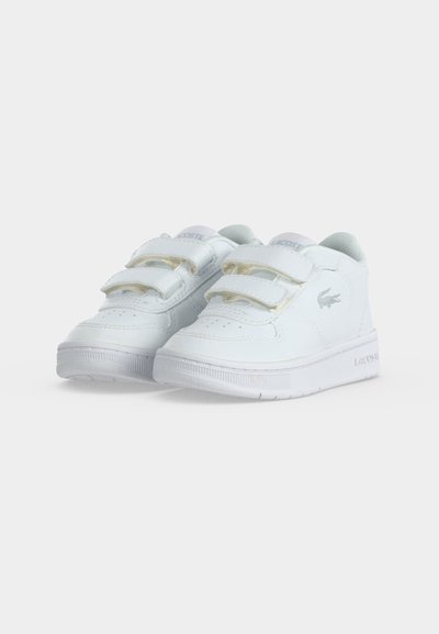 Чифт бели маратонки Lacoste с двойни велкро ленти и лого на крокодил отстрани, показани на обикновен бял фон.