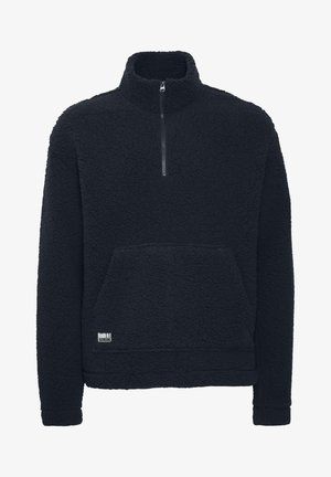 Svart fleece genser med høy krage, halv glidelås, teksturert ytre og en frontlomme. Har et lite logomerke.