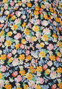 Tissu floral avec de petites fleurs colorées sur un fond noir, présentant des plis et une taille froncée. Matériau en coton doux.