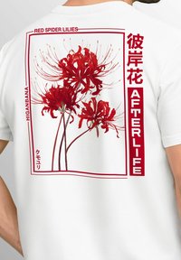 Weißes T-Shirt mit einem grafischen Design von roten Spinnenlilien, eingefasst in einem roten Rahmen, mit dem Text "HIGANBANA" und "AFTERLIFE" in Rot.
