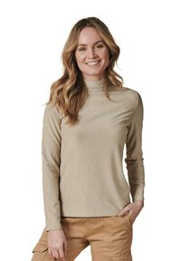 Langärmliges goldenes Oberteil mit hohem Kragen und subtilen Schimmer, aus weichem Stoff. Kombiniert mit beigen Cargo-Hosen für den Kontrast.