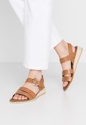 Brune læder wedge sandaler med flere krydsgående stropper, en rund spændeaccent og en struktureret espadrille-lignende sål.