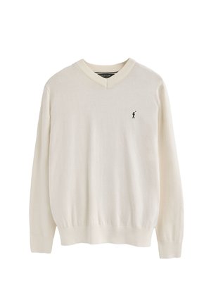 Crèmekleurige V-hals trui gemaakt van zacht materiaal, met lange mouwen en een subtiel zwart logo op de linkerborst. Soepele textuur, geribbelde manchetten.