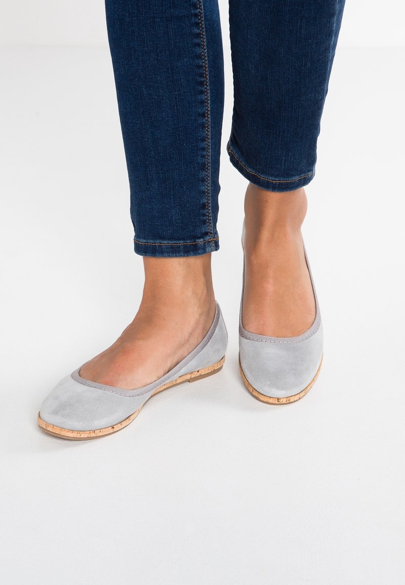 Ballerines en daim gris avec un bout rond et une semelle en liège ; le design minimaliste présente un contour contrastant le long du bord supérieur.