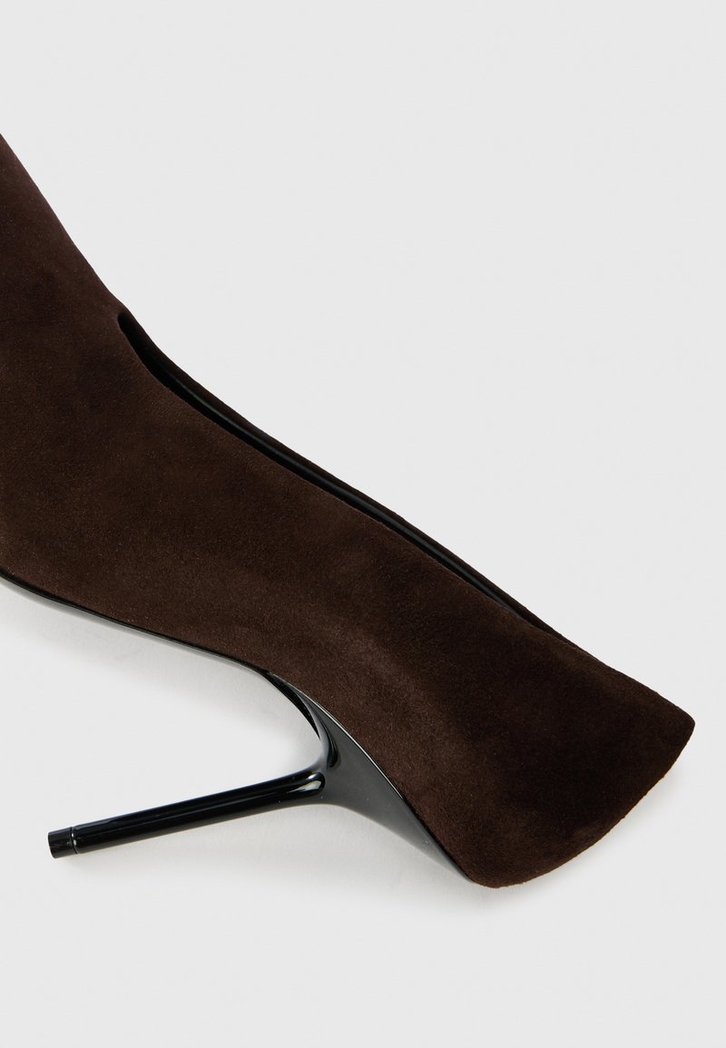 Stivaletto in suede marrone con tacco a spillo nero elegante e punta arrotondata. Presenta un design con tagli sui lati.