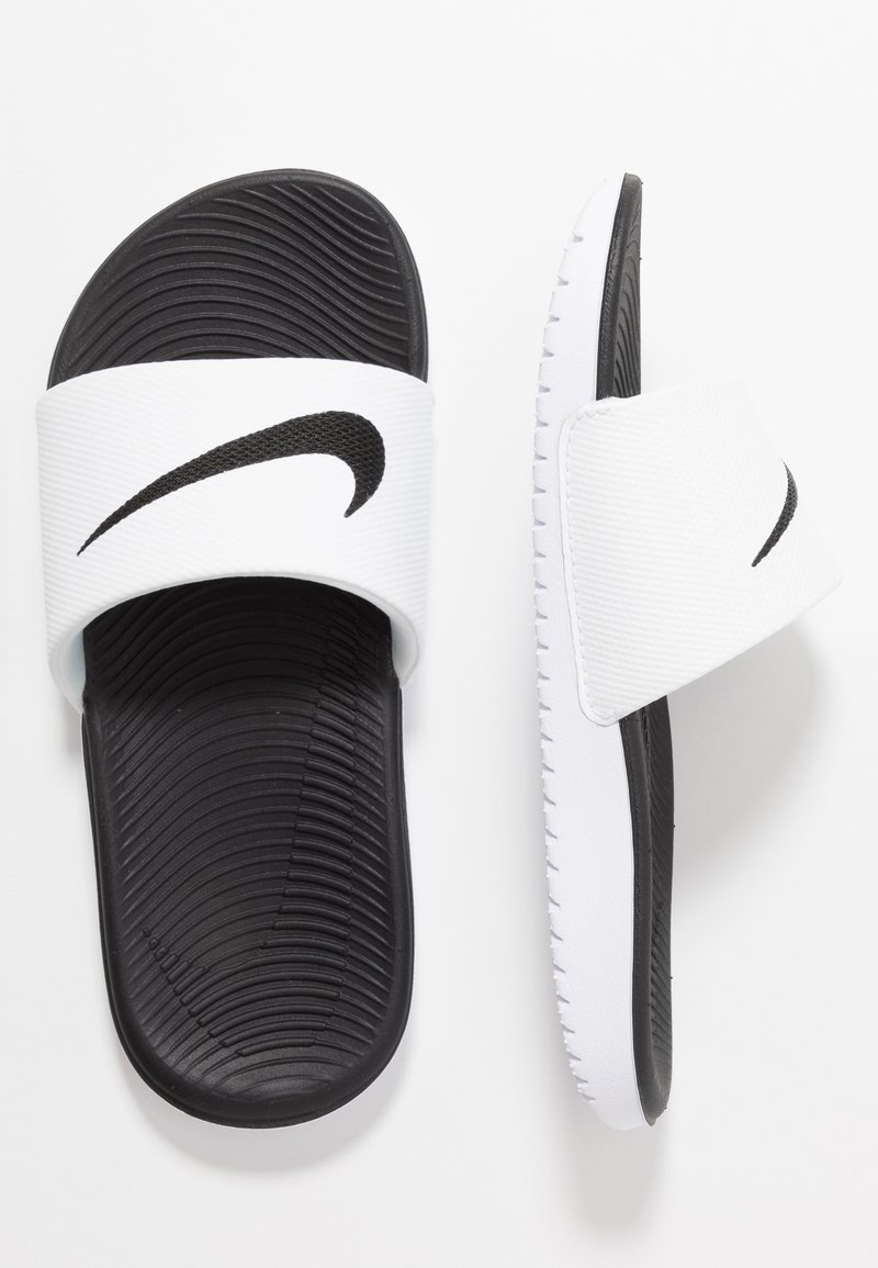 Valkoiset liukumäkipohjat mustalla kumipohjalla, leveä valkoinen hihna, jossa on musta Nike-swoosh-logo, ja uurteinen pohja.