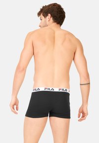 Boxer-culottes noirs en coton avec une taille blanche arborant le logo FILA en rouge et bleu. Coutures visibles et coupe ajustée.