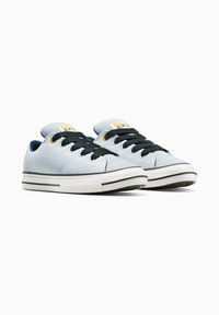 Sneaker di tela blu chiaro con lacci neri, punta in gomma bianca e strisce nere sulla suola. Etichetta gialla con logo sulla linguetta.