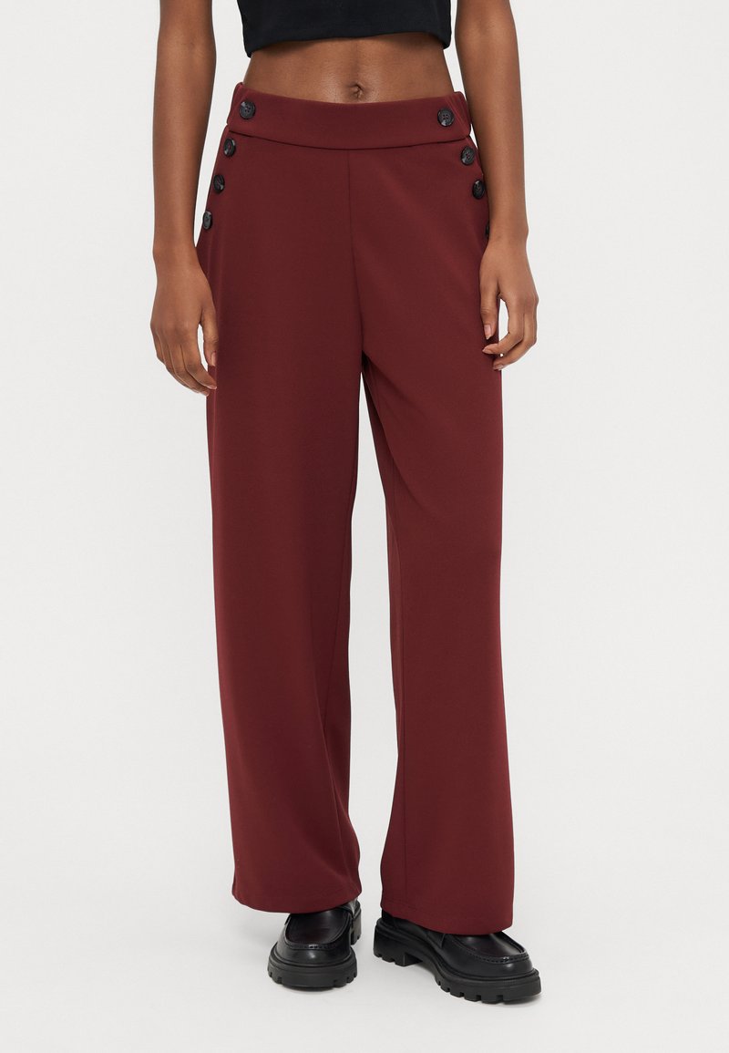 Pantalones de pierna ancha en color granate hechos de tela lisa, con una pretina alta y botones decorativos negros en el lateral.