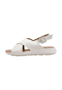 Sandalias de piel blanca tipo slingback con correas cruzadas, suela plana de goma, hebilla ajustable en el tobillo y textura suave acabada.