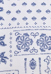 Valkoinen kangas, jossa on sininen, monimutkainen kuvio, jossa on kukka- ja paisley-tyylejä, välissä on pieniä pisteitä ja viivoja, pehmeä rakenne.