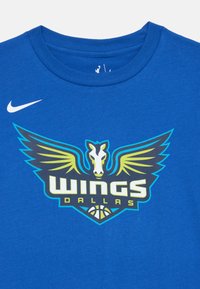 Blå bomullströja med en grafik av en häst och vingar i grönt och gult, med "WINGS DALLAS" i fet stil. Nike-logotyp i vitt.