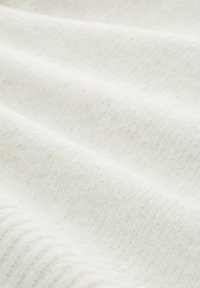 Bela teksturirana tkanina z mehkim, subtilnim vzorcem, ki ustvarja nežne valove. Material se zdi topel in udoben ter primeren za različne tekstilne aplikacije.