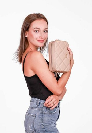 Beige prošívaná kabelka s uzávěrem na zip, má obdélníkový tvar a texturovaný povrch. Mezi detaily patří prošívání a kovové akcenty.