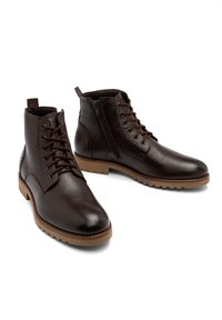 Brązowe skórzane botki za kostkę z okrągłymi noskami, sznurówką z przodu i zamkiem błyskawicznym z boku. Teksturowana powierzchnia i gumowe podeszwy zapewniające przyczepność.