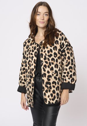 Animal print jacket features a beige and black leopard pattern, button front, and loose fit with black cuffs. Worn over a black top and pants.