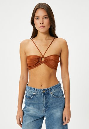 Brun satin bandeau-top med et samlet design og ringdetalje i midten. Tynde justerbare stropper og en glat tekstur. Bæres med blå jeans.