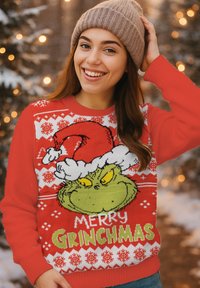 Maglione rosso con Il Grinch che indossa un cappello da Babbo Natale, fiocchi di neve e testo "MERRY GRINCHMAS". Tessuto a maglia, polsini e orlo a costine.