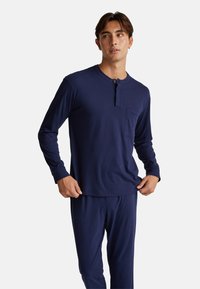 Conjunto de ropa de casa en azul marino que incluye una camiseta tipo henley de manga larga con bolsillo y pantalones a juego, fabricados en una suave y ligera tela.