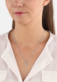 Sö silverhalsband med en sammanflätad droppe-pendant och en liten funklig detalj. Kedjan är ömtålig och har en subtil struktur.