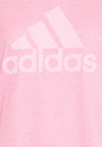 Rosa bomullströja med en stor vit Adidas-logga på framsidan, med en mjuk textur och en avslappnad design.