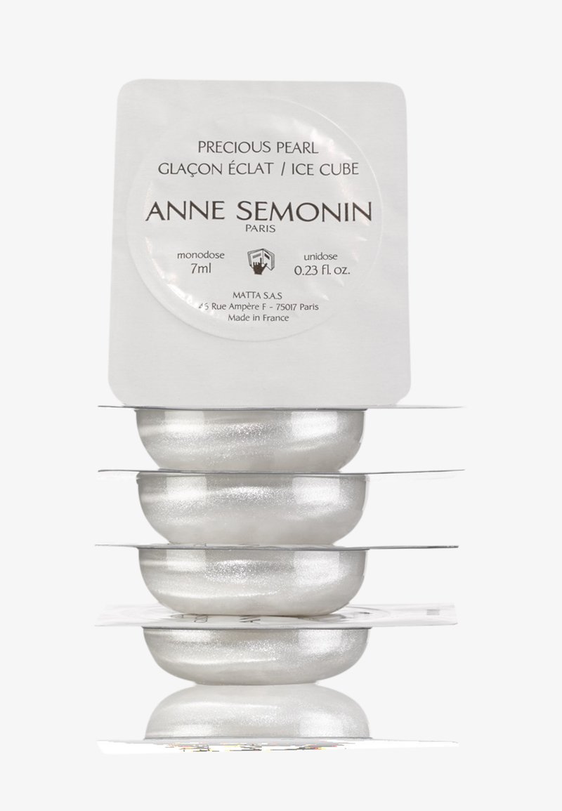 Un cube de glace Perle Précieuse en argent, contenu dans un emballage transparent. Présente une étiquette circulaire avec les détails de la marque en texte noir.