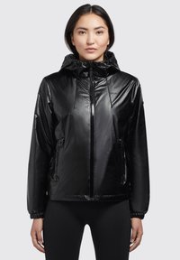 Chaqueta negra de nylon con acabado brillante, capucha ajustable y bolsillos laterales con cremallera. Presenta puños elásticos y un diseño de corte relajado.