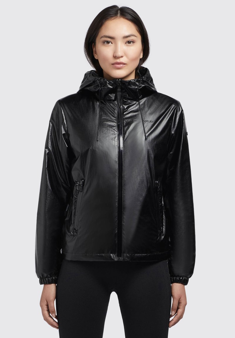 Chaqueta negra de nylon con acabado brillante, capucha ajustable y bolsillos laterales con cremallera. Presenta puños elásticos y un diseño de corte relajado.