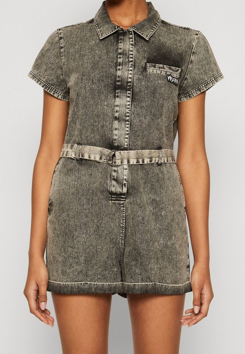 Combinaison courte en denim noir délavé à manches courtes, avec col, poche poitrine et ceinture assortie à boucle double anneau.