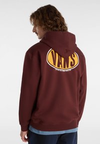 Maronfarvet hættebluse med et stort gult "VANS" logo på ryggen. Lavet af bomuldsmateriale, afslappet pasform, med snoretræk i hætten og ribbede cuffs.