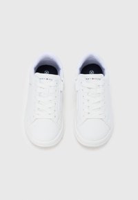 Ζεύγος λευκών παιδικών αθλητικών παπουτσιών Tommy Hilfiger με κορδόνια και πλαϊνά φερμουάρ, σε θέα από πάνω σε λευκό φόντο.