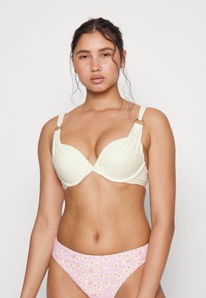Sutiã creme com bordado floral, suporte com aros e alças ajustáveis com acabamentos metálicos, combinado com calções de bikini rosa com riscas e estampa floral.