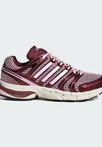 Chaussure de course avec une tige en mesh respirant de couleur rouge foncé et rose, ornée de rayures blanches, une semelle amortissante et des accents texturés.