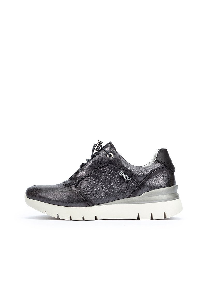 Zapatilla de deporte de cuero negro con panel lateral texturizado, diseño con cordones, suela acolchada y una suela exterior clara en contraste.