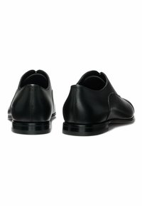 Black leather shoes with a smooth finish, rounded toe, and subtle stitching. Features a low, textured sole and no visible hardware.