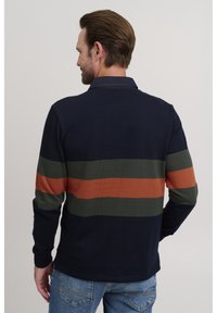 Mornarska polo majica dugih rukava s horizontalnim prugama u maslinasto zelenoj i hrđavo narančastoj boji, s ovratnikom i suptilnom teksturom.