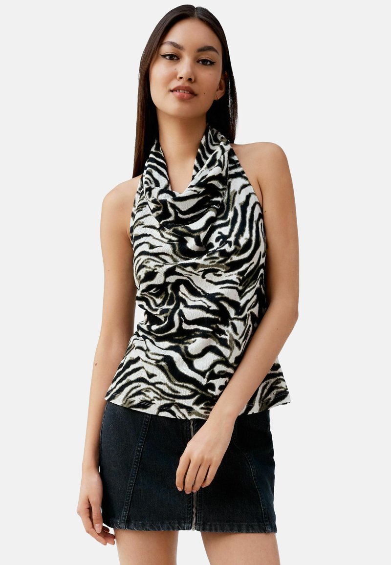 Haut à col châle en tissu imprimé zèbre noir et blanc ; texture douce ; coupe ajustée, associé à une mini-jupe en denim noire.