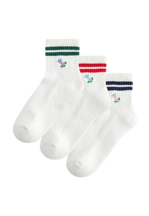 Tre hvide ankelsokker med ribbede manchetter, hver med to striber i grøn, rød eller marineblå og en lille broderet blomst nær anklen.