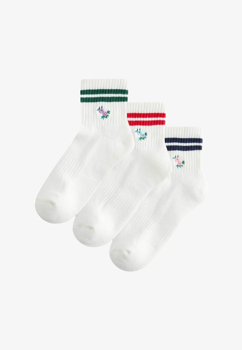 Trois chaussettes blanches à la cheville avec des bords côtelés, chacune présentant deux rayures en vert, rouge ou marine, et une petite fleur brodée près de la cheville.