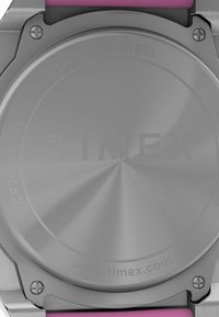 Fondello in acciaio inossidabile con finitura spazzolata, timbrato "TIMEX". Presenta un cinturino rosa e angoli arrotondati. Include la batteria di tipo CR2016.