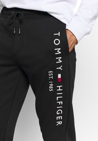 Zwarte sweatpants gemaakt van een katoenmix met wit geborduurd logo "TOMMY HILFIGER" en "EST. 1985" langs de zijkant, met verstelbaar trekkoord.