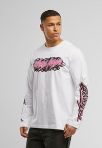Long-sleeve white cotton t-shirt featuring a large black and pink graphic design on the front and additional graphics on the sleeves.