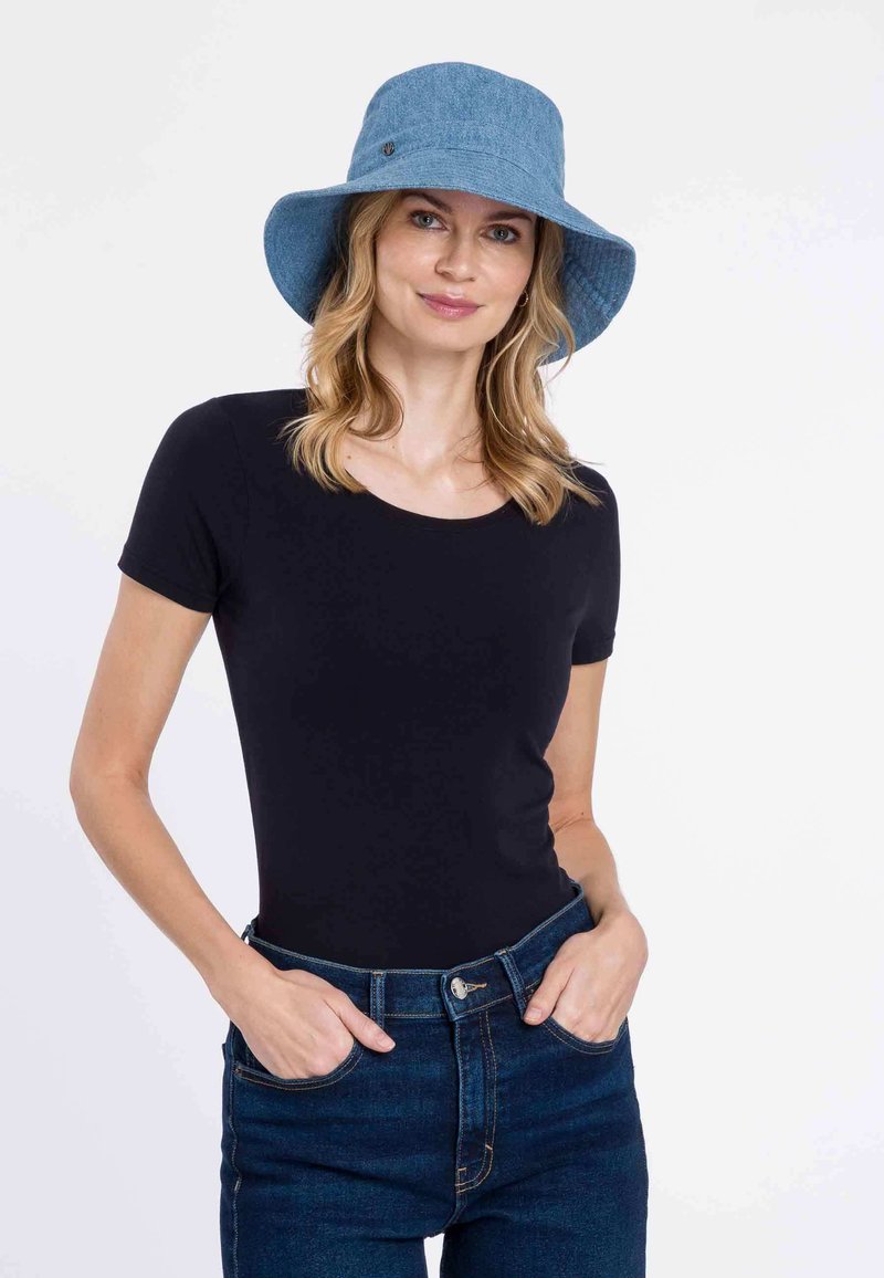 Kék denim kalap, rövid ujjú fekete top és sötétkék magasderék farmernadrág; egyszerű dizájn, testhez álló sziluett és felhajtott ujjak.