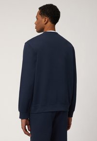 Navyblauer Sweatshirt mit langen Ärmeln, Rundhalsausschnitt und gerippten Bündchen. Hergestellt aus einem weichen Stoff, mit lockerer Passform und glatter Textur.