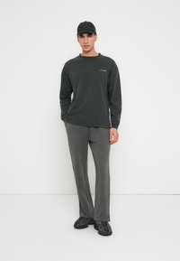 Szary longsleeve z okrągłym dekoltem i czarne spodnie. Czapka w kolorze czarnym oraz ciemne trampki dopełniają strój. Prosty, casualowy design.