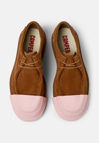 Paio di scarpe in suede marrone con lacci, punte in gomma rosa e marchio "CAMPER" all'interno, su sfondo bianco.
